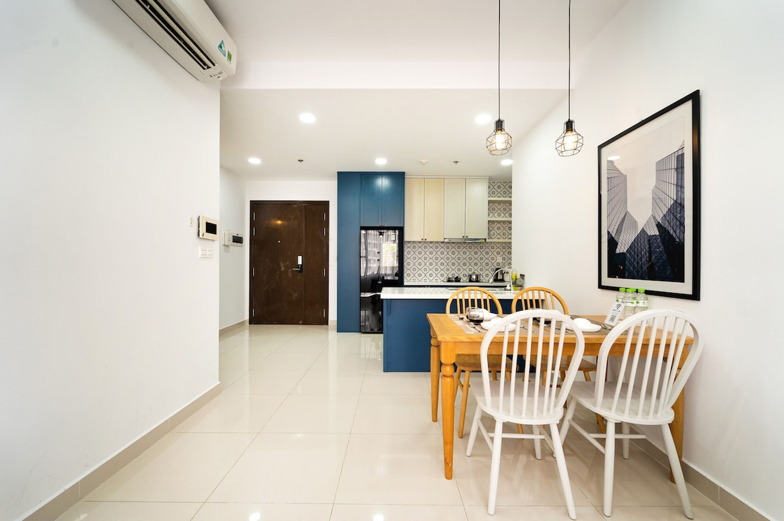 Una cocina moderna con armarios azules, una encimera blanca y un comedor con una mesa de madera y sillas blancas.