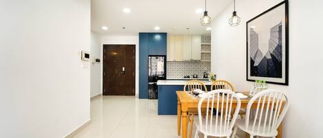 Una cocina moderna con armarios azules, una encimera blanca y un comedor con una mesa de madera y sillas blancas.