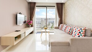 Una sala de estar moderna con un sofá, televisor y un balcón con vista a la ciudad.