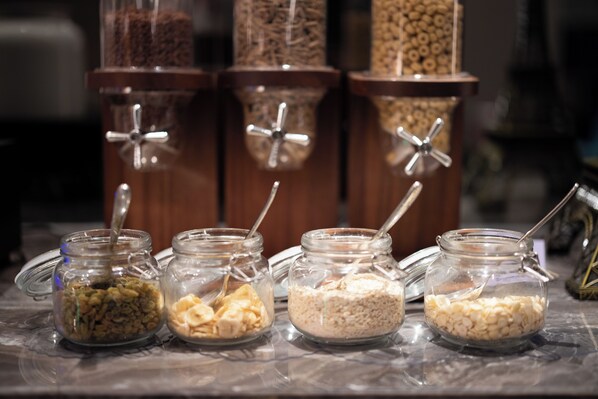 Four glass jars with metal lids on a marble countertop, each containing different food items.