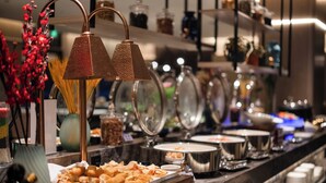Disposição de buffet com diversos recipientes de comida e um abajur decorativo.