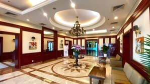 A lobby with a marble floor, a central chandelier, a reception desk, and a seating area with a sofa and a bench. - GEM Residence - The Manor Central (Ho Chi Minh City)