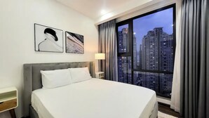 A hotel room with a large bed, a nightstand, a lamp, and two framed artworks on the wall. - GEM Residence - The Manor Central (Ho Chi Minh City)
