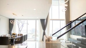 A modern living room with a dining area, a sofa, and a staircase. - The Serenity Sky Villas D3 (Ho Chi Minh City)