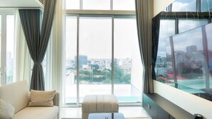 A modern living room with a sofa, ottoman, and a large TV. - The Serenity Sky Villas D3 (Ho Chi Minh City)