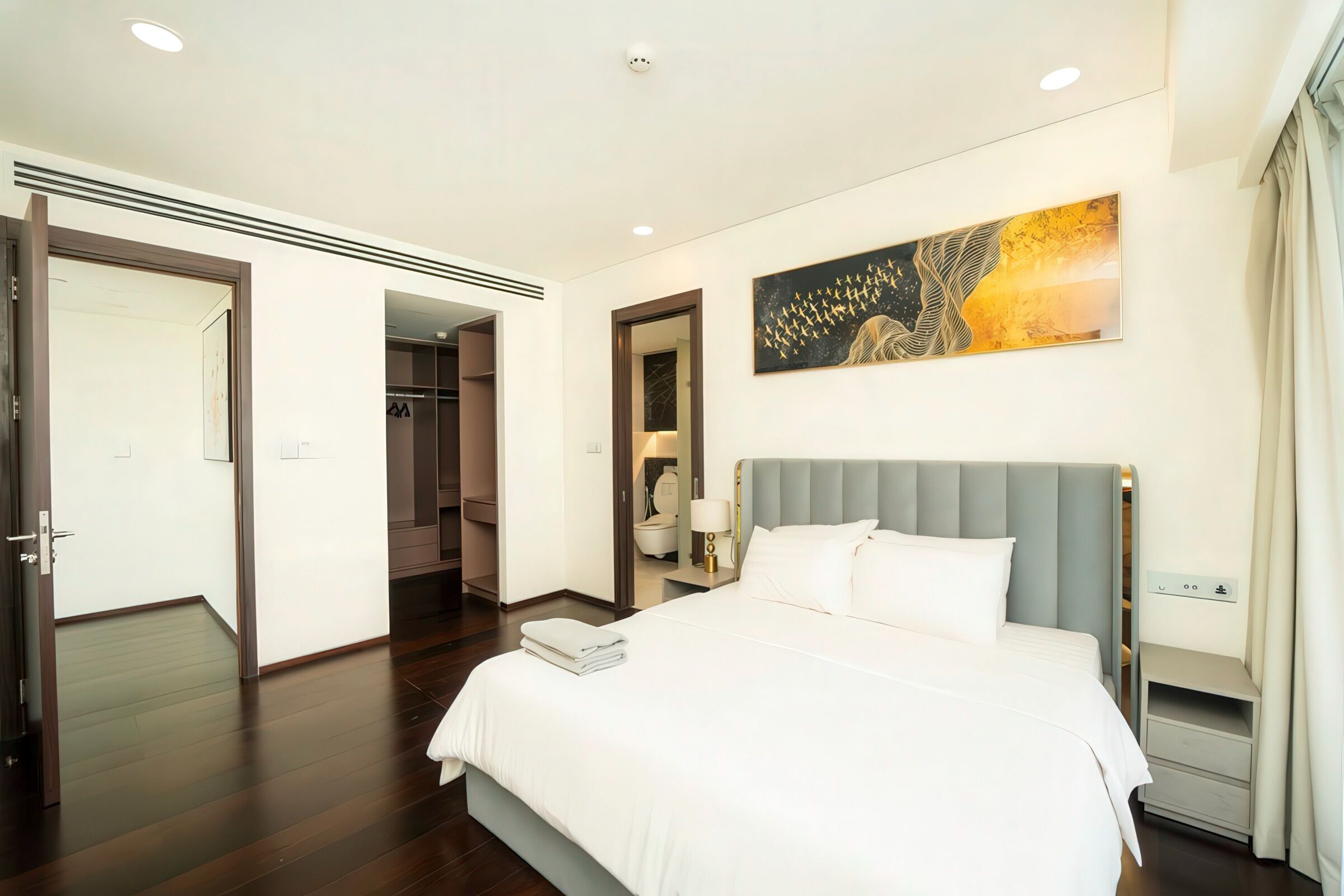 Een hotelkamer met een groot bed, een garderobe, een spiegel en een schilderij aan de muur.