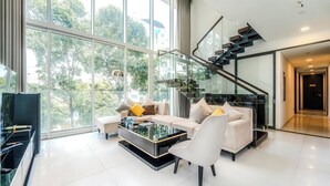 A modern living room with a glass coffee table, a sofa, and a piano. - The Serenity Sky Villas D3 (Ho Chi Minh City)