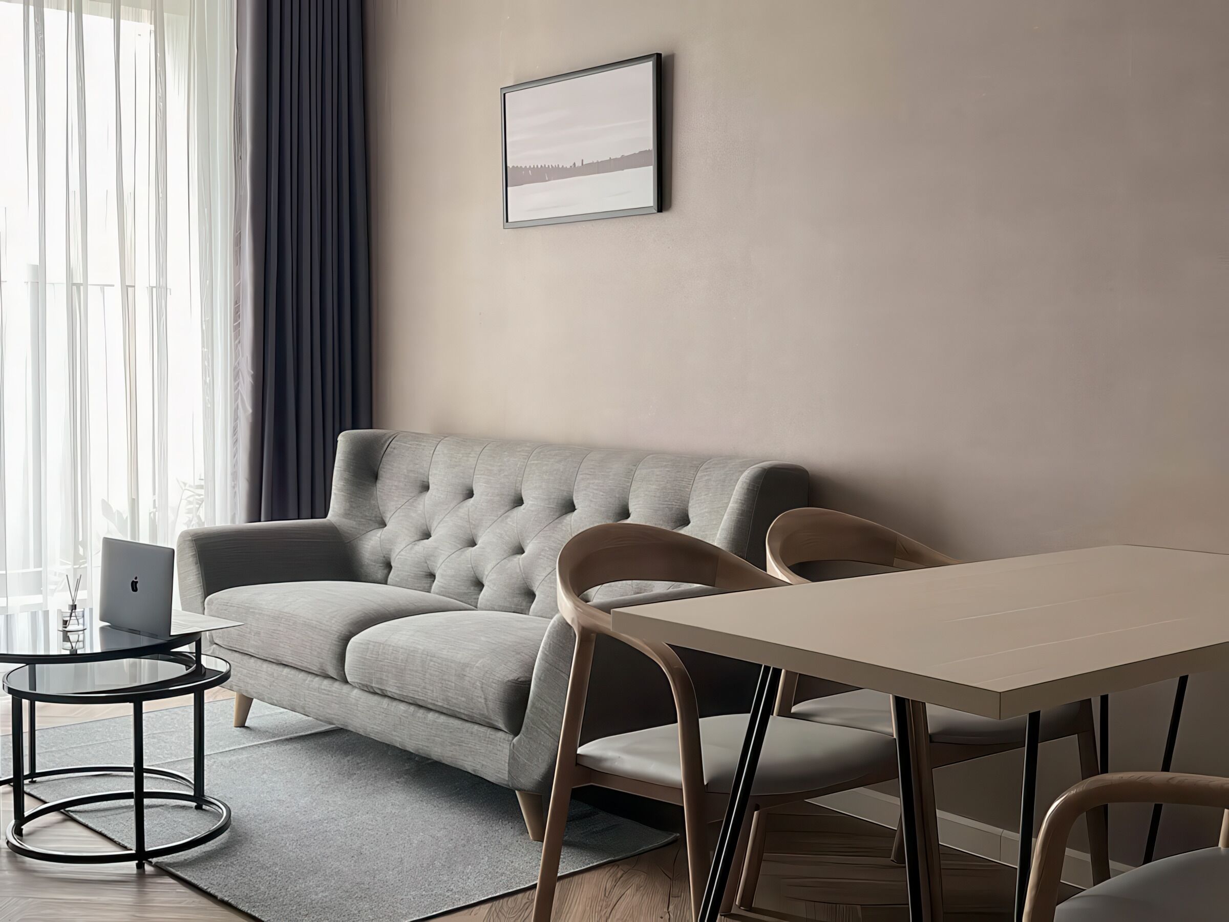 A modern living room with a grey sofa, a round coffee table, and a dining table with chairs.