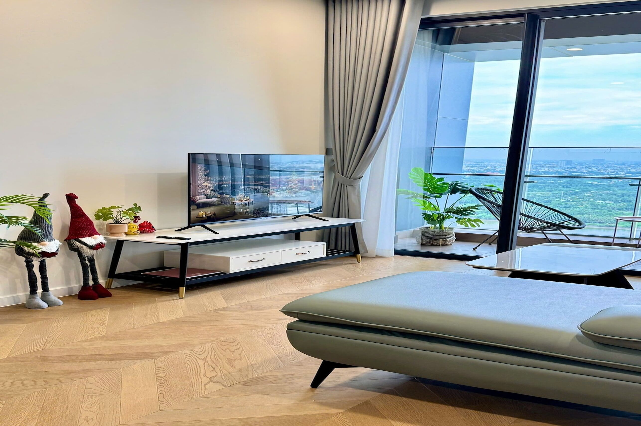 Un salon moderne doté d’un grand téléviseur à écran plat, d’un canapé, d’une table à manger et d’un balcon offrant une vue sur la ville.