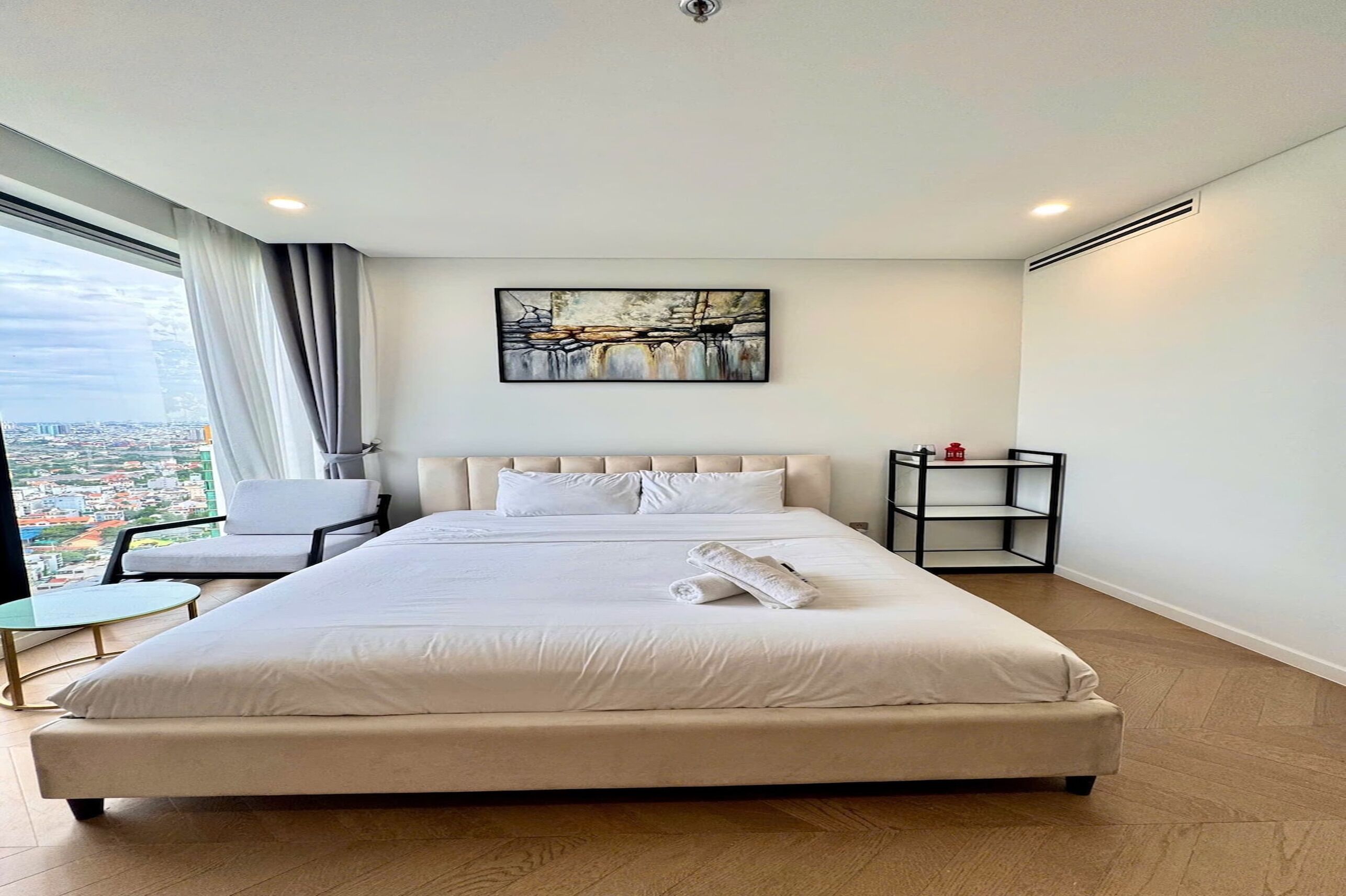 Una camera d'albergo moderna con un letto grande, una sedia, un tavolino e un comodino.