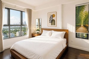 A hotel room with a large bed, a nightstand, a mirror, a window with a city view, and a framed artwork on the wall. - The Sun Avenue - Lalaland & Chill Sky Pool (Ho Chi Minh City)