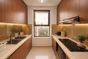 A modern kitchen with wooden cabinets, a window, and a view of buildings. - The Sun Avenue - Lalaland & Chill Sky Pool (Ho Chi Minh City)