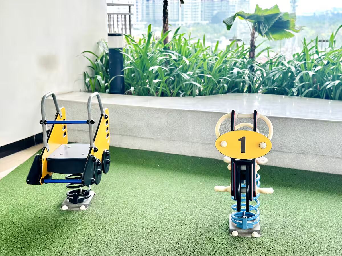 Due dispositivi robotici su erba sintetica, con vista su un edificio e vegetazione sullo sfondo.