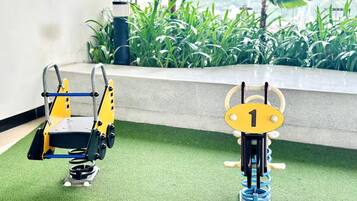 Due dispositivi robotici su erba sintetica, con vista su un edificio e vegetazione sullo sfondo.