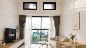 A modern living room with a TV, sofa, dining table, and chairs. - The Sun Avenue - Lalaland & Chill Sky Pool (Ho Chi Minh City)