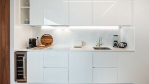 Een moderne keuken met witte kastjes, een inbouwoven, een broodrooster, een blender en een waterkoker.