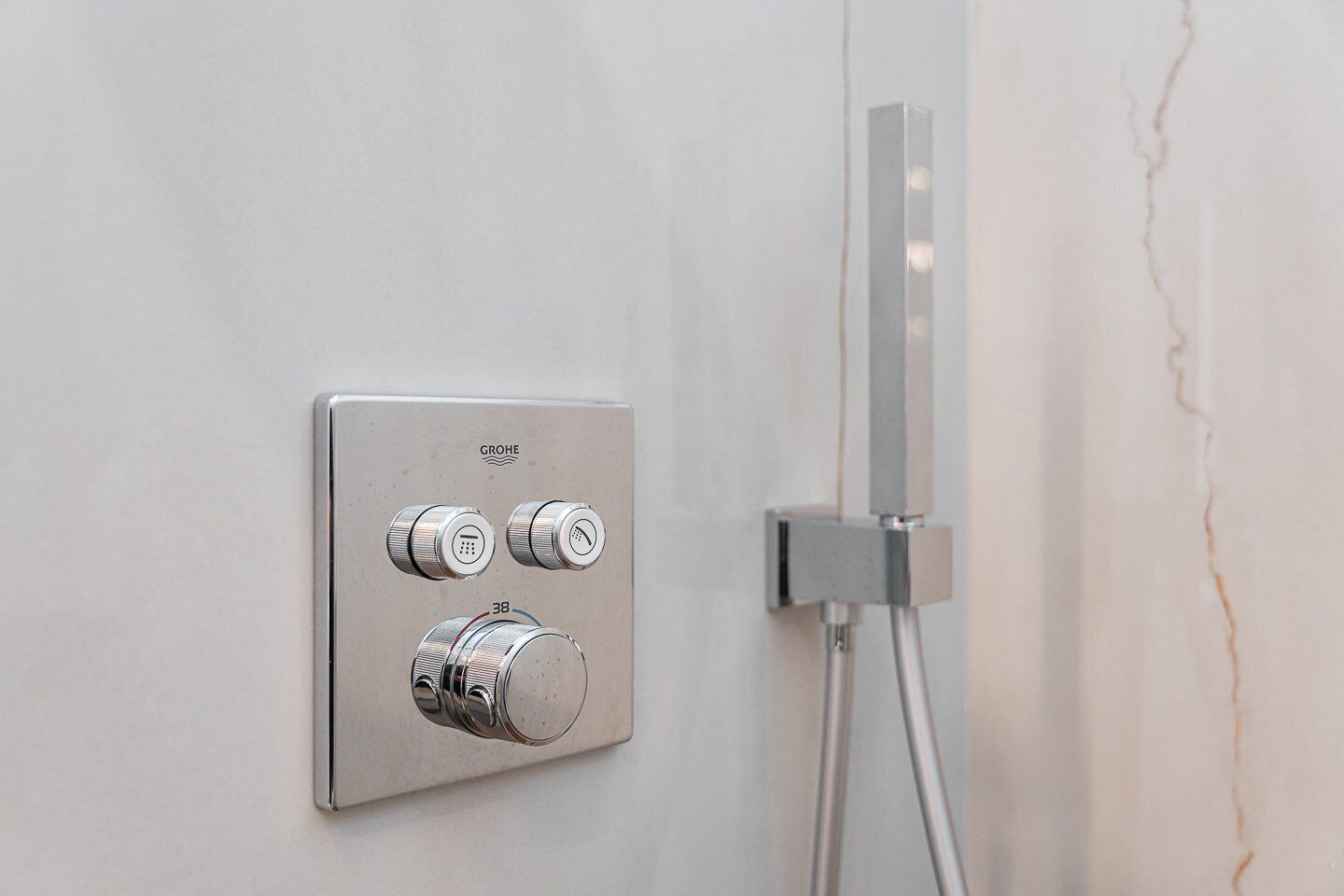Een GROHE douchepaneel met verschillende knoppen en een handdouche.