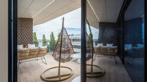 Een modern interieur met rieten meubels, een hangstoel en uitzicht op een gebouw aan de overkant van het water.