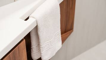 A white towel hanging on a wooden towel rack in a bathroom.