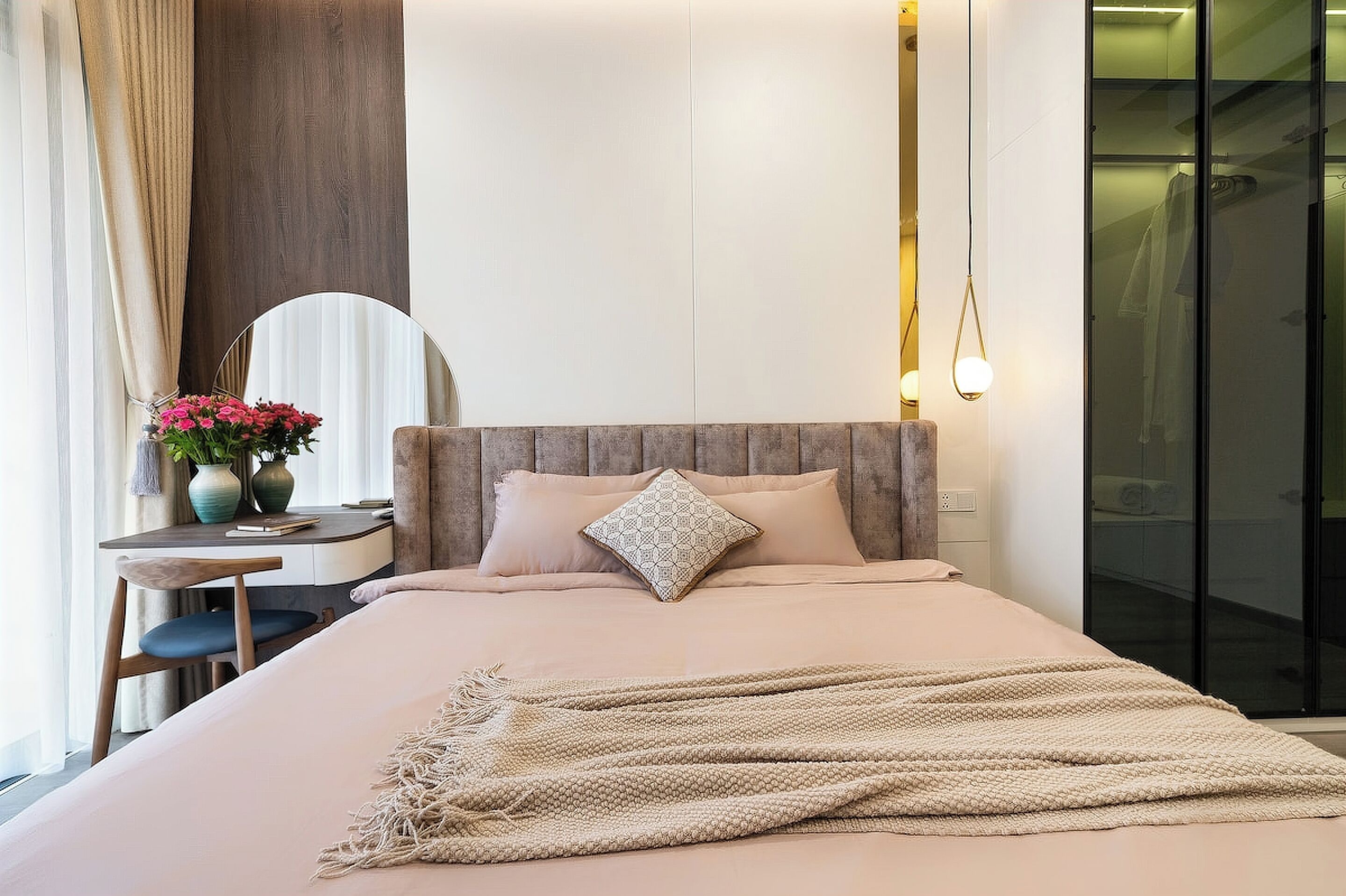 A modern bedroom with a bed, bedside table, lamp, and a view of a bathroom.