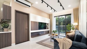 A modern living room with a flat-screen TV, dark sofa, and a dining area with a round table. - Century Diamond Alnata Plus - Tan Phu (Ho Chi Minh City)