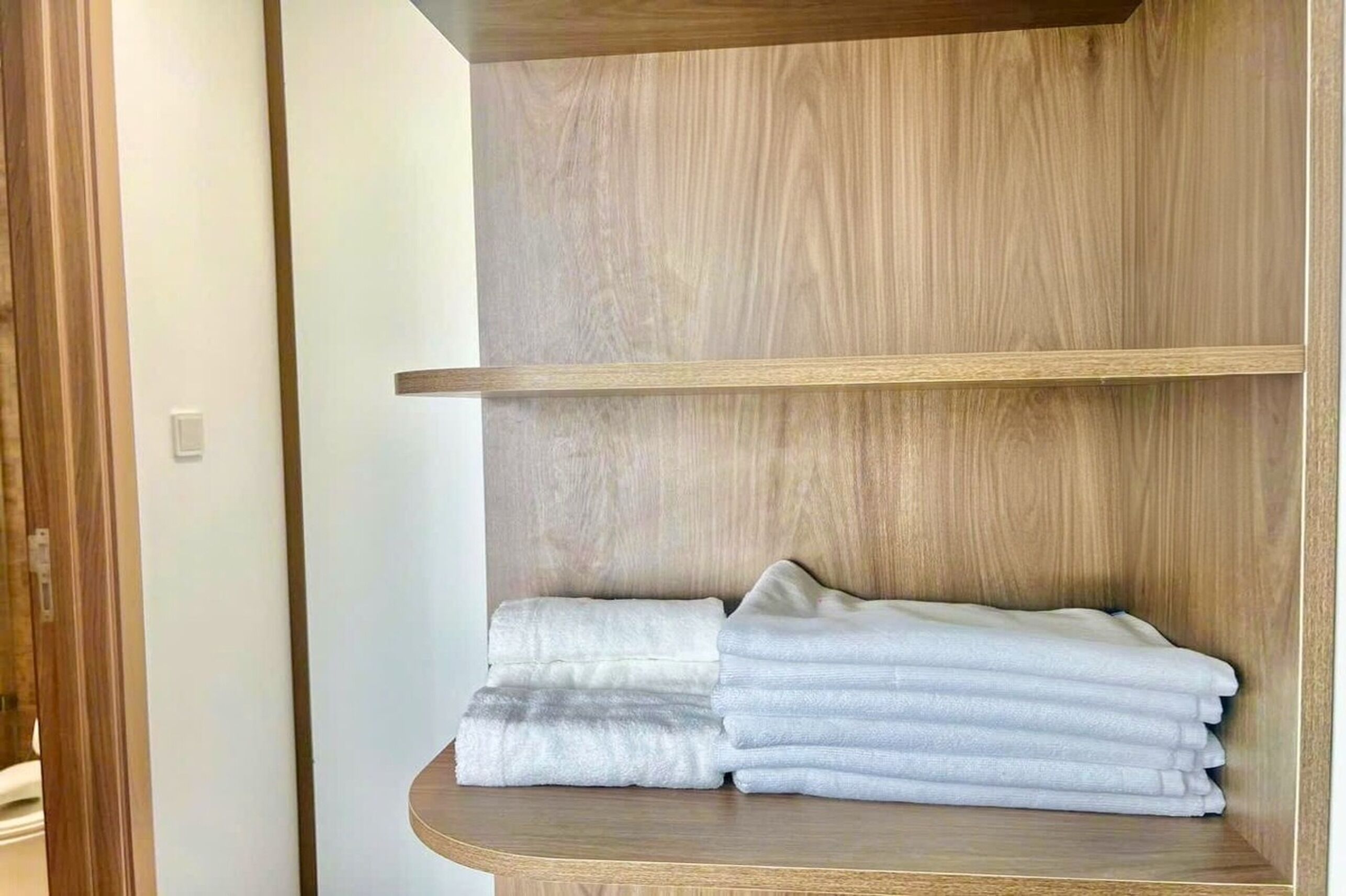 Un rincón de una habitación con un estante de madera que sostiene toallas dobladas.
