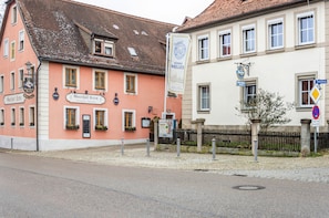 A street view with buildings, including a pink building with a sign 'Gasthof Heller' and a white building with a sign 'Schulze'.