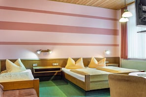 A hotel room with two beds, a chair, a small table, and a window with curtains.