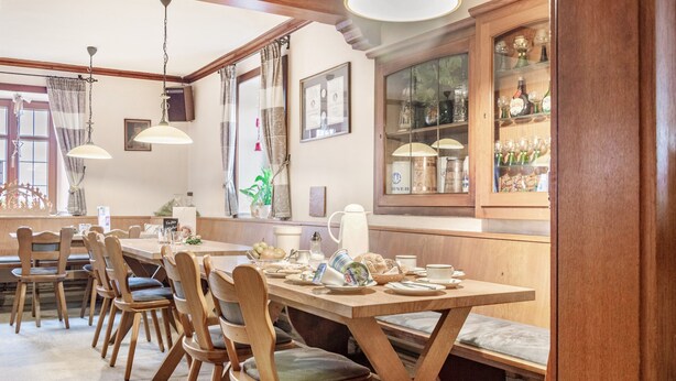 Un espace repas avec des meubles en bois, une longue table et un buffet doté de portes en verre.