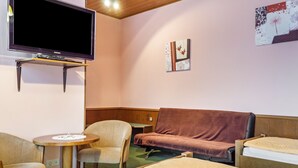 Une pièce comprenant un lit, un canapé, une chaise, une petite table et un téléviseur.