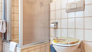 A bathroom with a shower, toilet, and a towel rack.