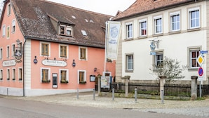 A street view with buildings, including a pink building with a sign 'Gasthof Heller' and a white building with a sign 'Schulze'. - Room 2 - Double room with Wi-Fi (Lehrberg)