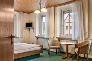 A room with a bed, two chairs, a small table, a TV, and large windows with curtains. - Room 3 - Double room with Wi-Fi (Lehrberg)