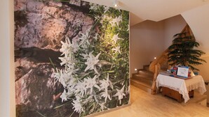 A hallway with a large floral mural, a staircase, and a small table with a book and a plant.