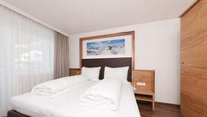 A hotel room with a bed, a nightstand, a wooden wardrobe, and a framed picture on the wall.