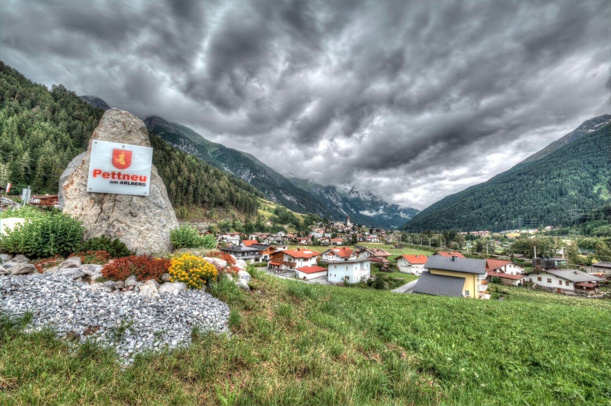 A mountainous village with a prominent rock sign labeled 'Pettneu am ARLBERG.'