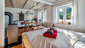Una habitación con cama, escritorio, silla, estufa y ventana.