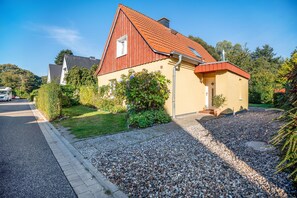 A two-story house with a red roof, a small attached garage, and a gravel driveway. - Apartment 'Öko Fewo Sturmmöwe' with Private Terrace, Private Garden and Wi-Fi (Kiel)