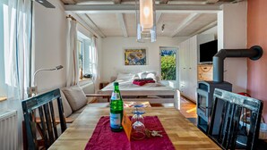 Una habitación acogedora con una cama, una mesa con una botella y vasos, techo de madera y una chimenea.