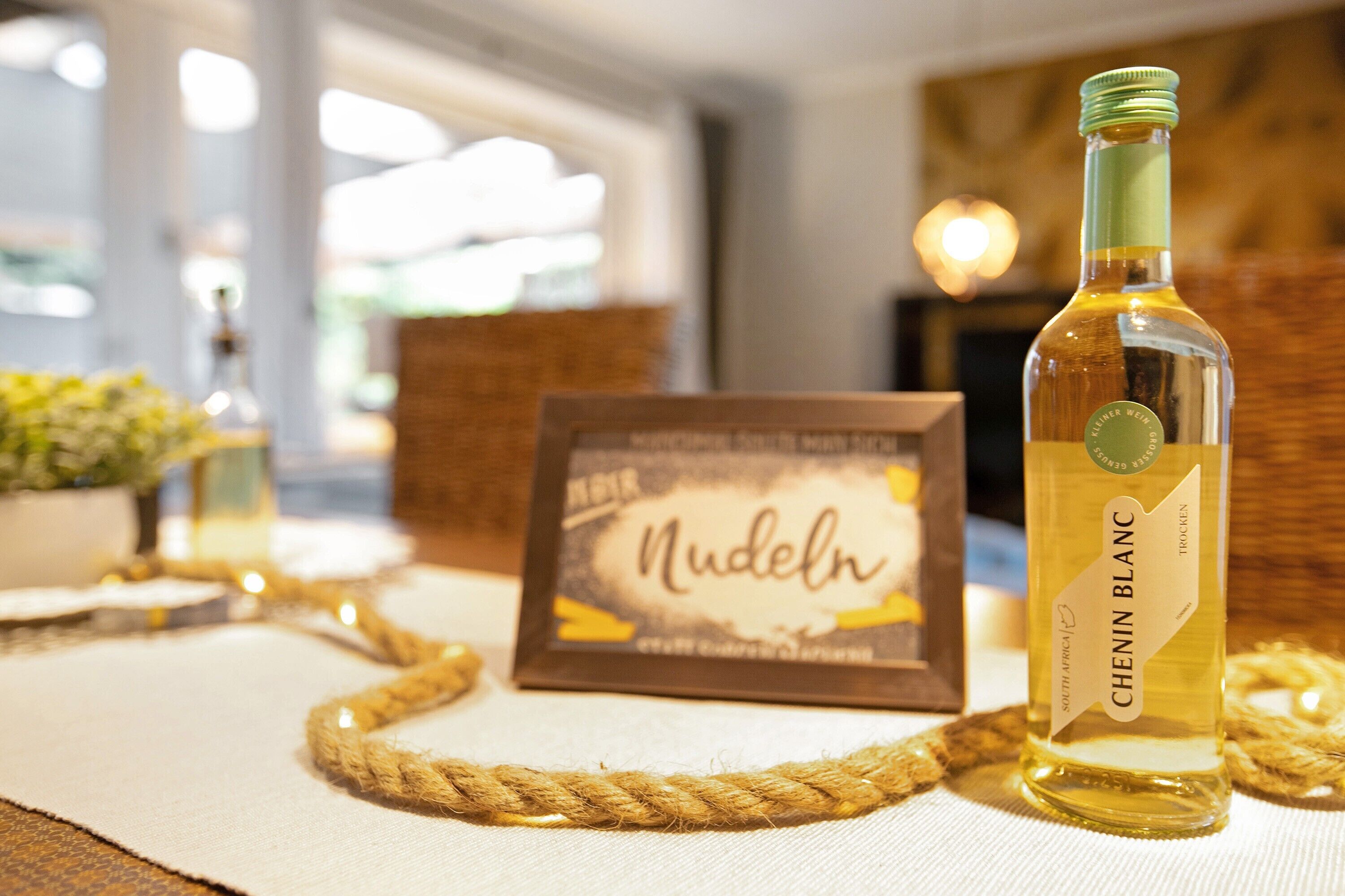 A bottle of Chenin Blanc wine, a framed menu, and a rope on a table.