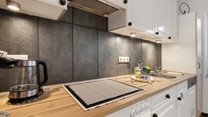 A modern kitchen with a wooden countertop, stainless steel appliances, and white cabinetry.