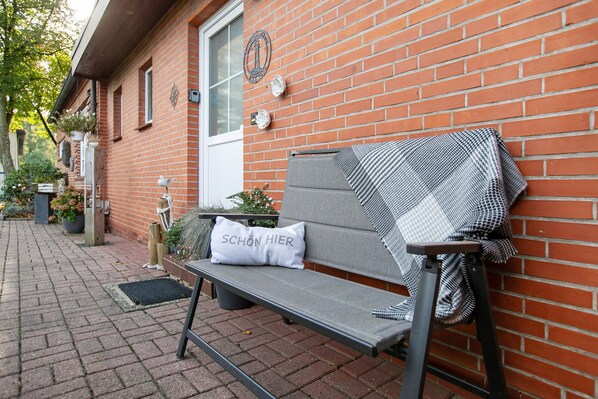 Un banc avec un coussin et une couverture, adossé à un mur de briques.