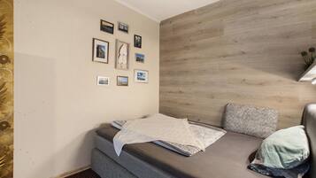 Een kleine kamer met een bed, een muur met ingelijste foto's en een houten accentmuur.