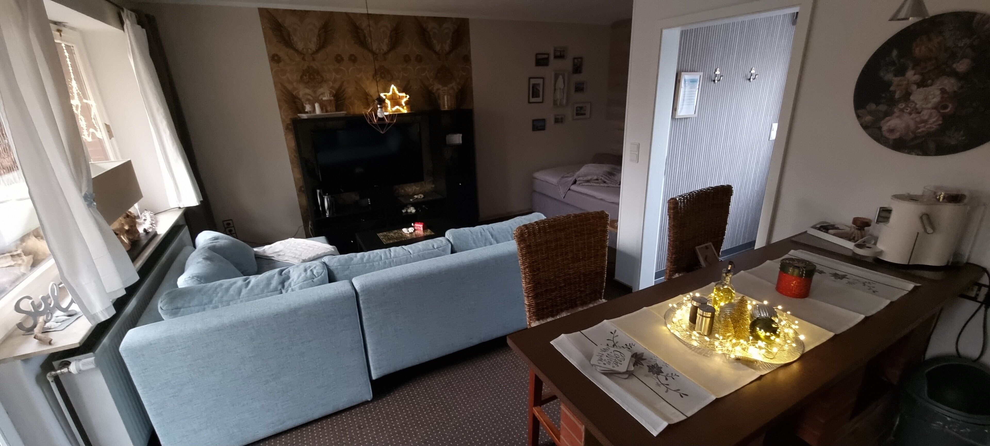 A living room with a sofa, a TV, a dining table with a placemat, and a decorative light.