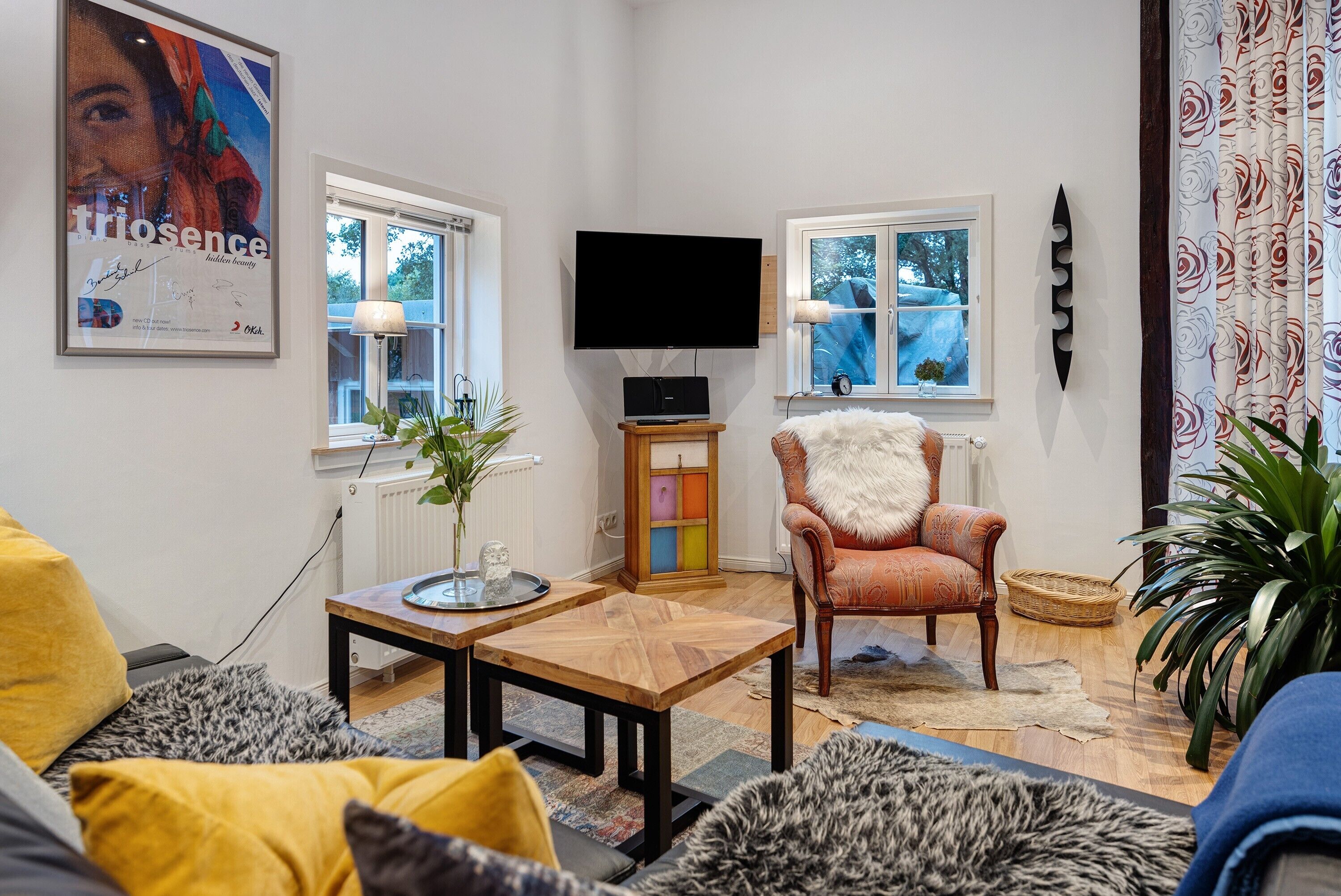 Un salon avec un canapé, un fauteuil, une table basse, un téléviseur et une affiche accrochée au mur.
