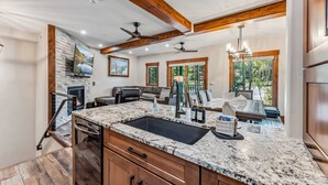A modern kitchen with a granite countertop, wooden cabinets, and a built-in sink. - Breck Ski-in Retreat – Walk to Gondola & Lifts (Breckenridge)