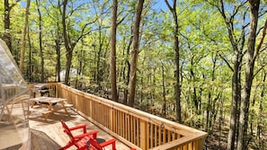 Une terrasse avec un barbecue et un espace salon donnant sur une forêt.