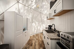 Eine kleine Küche mit weißen Schränken, Holzboden und integriertem Backofen.