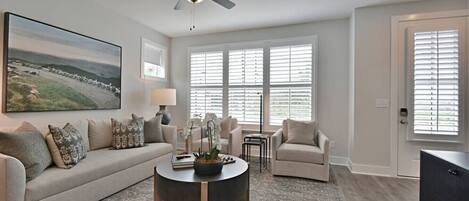 A living room with a sofa, armchairs, a coffee table, and a ceiling fan.