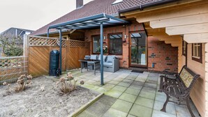 A patio with a covered seating area, a bench, and a garden bed.